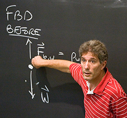 Photo of faculty member at a blackboard during a class